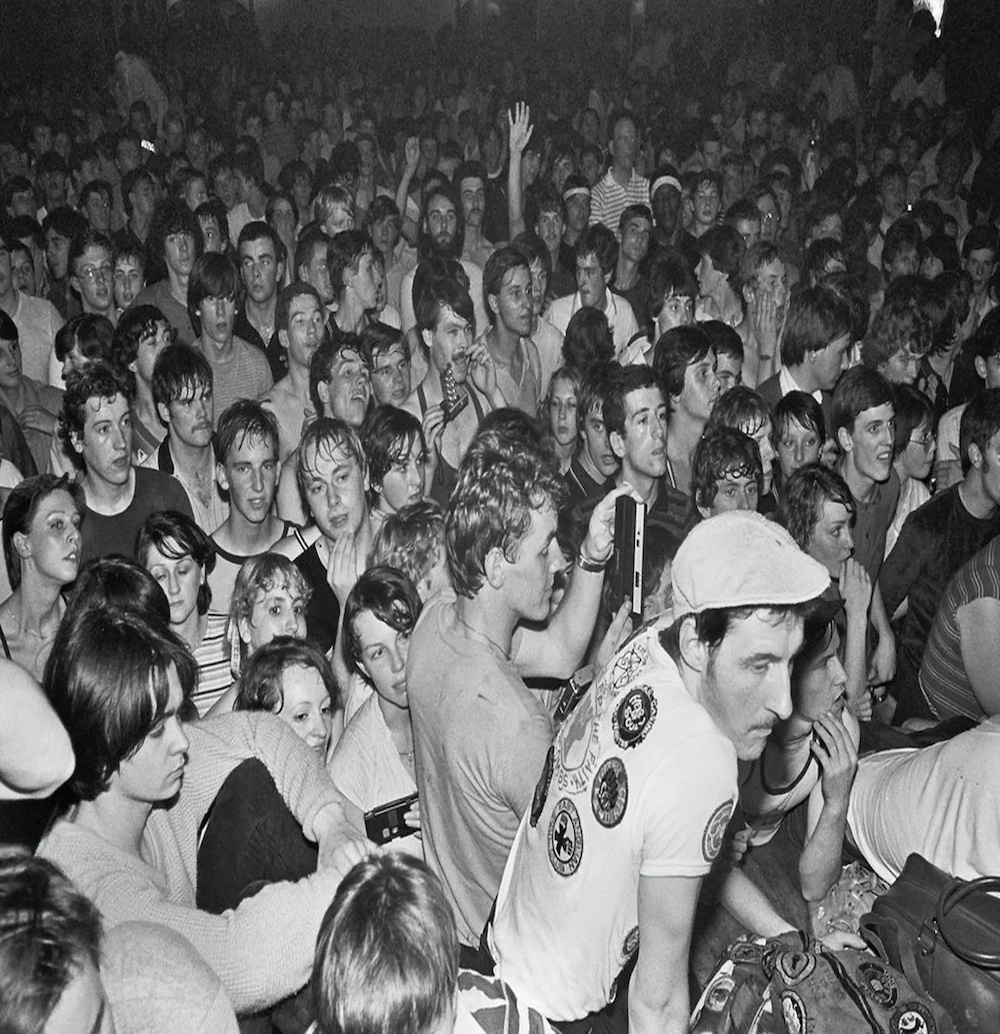 A crowd of people on a dance floor with a hand in the air